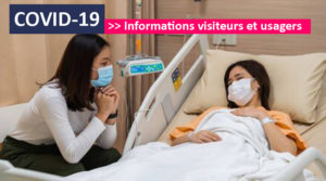 Photo d'une patiente dans son lit et une visiteuse. Les deux personnes masquées